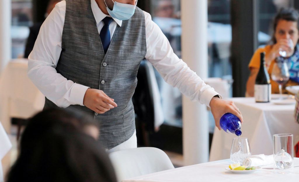 Masked waiter serving water